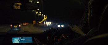Movie still from “Locke” (2013), directed by Steven Knight – A person is driving a car at night with headlights on; Medium shot, Over the shoulder angle