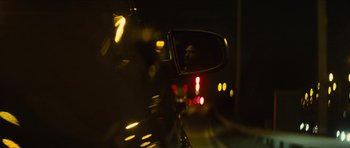 Movie still from “Locke” (2013), directed by Steven Knight – A car's side view mirror reflecting the lights at night; Close Up shot, Over the shoulder angle