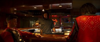 Movie still from “Logan Lucky” (2017), directed by Steven Soderbergh – A man standing at a bar preparing a drink; Medium shot, Low angle