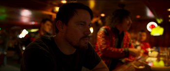 Movie still from “Logan Lucky” (2017), directed by Steven Soderbergh – A person sitting at a table; Close Up shot, Over the shoulder angle