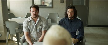 Movie still from “Logan Lucky” (2017), directed by Steven Soderbergh – Two men sitting in front of each other in front of a white wall; Medium shot, Over the shoulder angle