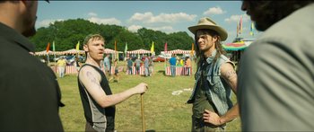 Movie still from “Logan Lucky” (2017), directed by Steven Soderbergh – Two men standing next to each other on a field; Medium shot, Over the shoulder angle