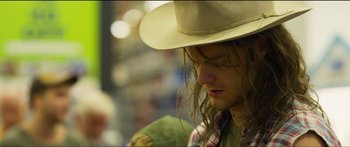 Movie still from “Logan Lucky” (2017), directed by Steven Soderbergh – A man with long hair wearing a cowboy hat; Close Up shot, Over the shoulder angle