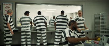 Movie still from “Logan Lucky” (2017), directed by Steven Soderbergh – A man in prison stripes is looking in the mirror; Wide shot, High angle