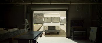 Movie still from “Logan Lucky” (2017), directed by Steven Soderbergh – A white truck is parked in a garage door; Wide shot, Low angle
