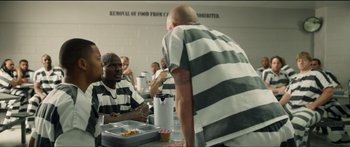 Movie still from “Logan Lucky” (2017), directed by Steven Soderbergh – A group of men in striped shirts eating food; Medium shot, Over the shoulder angle