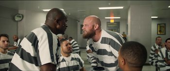 Movie still from “Logan Lucky” (2017), directed by Steven Soderbergh – A group of men in prison uniforms talking to each other; Medium shot, Over the shoulder angle