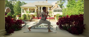 Movie still from “Logan Lucky” (2017), directed by Steven Soderbergh – A man is doing yoga in the backyard of a house; Wide shot, Low angle