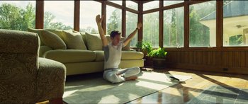 Movie still from “Logan Lucky” (2017), directed by Steven Soderbergh – A man sitting on the ground in a living room; Wide shot, Low angle