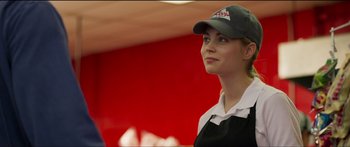 Movie still from “Logan Lucky” (2017), directed by Steven Soderbergh – A woman wearing a hat standing next to a red wall; Close Up shot, Over the shoulder angle