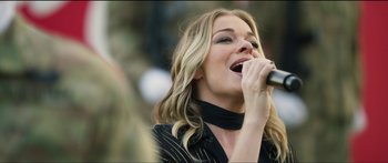 Movie still from “Logan Lucky” (2017), directed by Steven Soderbergh – A beautiful blonde woman singing into a microphone; Close Up shot, Over the shoulder angle