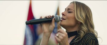 Movie still from “Logan Lucky” (2017), directed by Steven Soderbergh – A woman holding a microphone up to her mouth; Close Up shot, Low angle