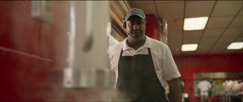 Movie still from “Logan Lucky” (2017), directed by Steven Soderbergh – A man wearing an apron standing in front of a mirror; Medium shot, Low angle