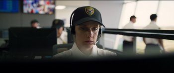 Movie still from “Logan Lucky” (2017), directed by Steven Soderbergh – A woman wearing a hat and headphones looking at a computer screen; Close Up shot, Over the shoulder angle
