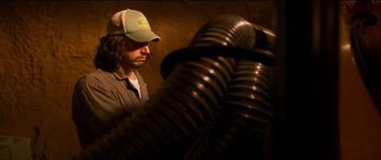 Movie still from “Logan Lucky” (2017), directed by Steven Soderbergh – A man wearing a hat looking down at a vent; Medium shot, Low angle