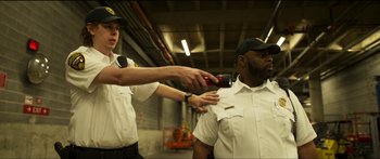 Movie still from “Logan Lucky” (2017), directed by Steven Soderbergh – Two men in white shirts and blue hats one of which is using a hair trimmer; Medium shot, Low angle