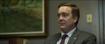 Movie still from “Logan Lucky” (2017), directed by Steven Soderbergh – A person wearing a suit and tie; Close Up shot, Over the shoulder angle