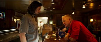 Movie still from “Logan Lucky” (2017), directed by Steven Soderbergh – Two men sitting at a bar talking to each other; Medium shot, Over the shoulder angle