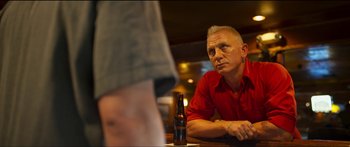 Movie still from “Logan Lucky” (2017), directed by Steven Soderbergh – A man sitting at a table in front of a bottle of beer; Close Up shot, Over the shoulder angle