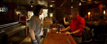 Movie still from “Logan Lucky” (2017), directed by Steven Soderbergh – A man standing at a bar talking to a woman; Medium shot, Over the shoulder angle