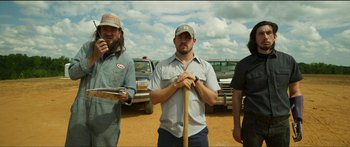 Movie still from “Logan Lucky” (2017), directed by Steven Soderbergh – A group of men standing next to each other on a dirt field; Medium shot, Low angle