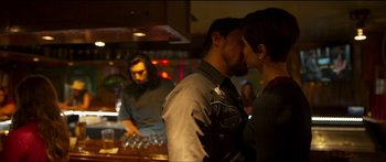 Movie still from “Logan Lucky” (2017), directed by Steven Soderbergh – A man and a woman kissing in front of a bar; Medium shot, Over the shoulder angle