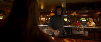 Movie still from “Logan Lucky” (2017), directed by Steven Soderbergh – A man standing at a bar holding a drink; Medium shot, Over the shoulder angle