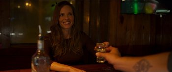 Movie still from “Logan Lucky” (2017), directed by Steven Soderbergh – A woman sitting at a table with a glass of alcohol; Close Up shot, Over the shoulder angle