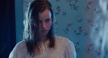 Movie still from “Lore” (2012), directed by Cate Shortland – A woman with wet hair standing in front of a floral wallpaper; Close Up shot, Over the shoulder angle