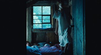 Movie still from “Lore” (2012), directed by Cate Shortland – A woman in a white nightgown standing on a bed; Wide shot, Low angle