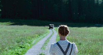 Movie still from “Lore” (2012), directed by Cate Shortland – A woman walking down a dirt road towards a car; Wide shot, High angle