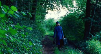 Movie still from “Lore” (2012), directed by Cate Shortland – A woman in a blue dress walking down a path with suitcases; Wide shot, Low angle