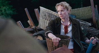 Movie still from “Lore” (2012), directed by Cate Shortland – A woman sitting on a chair holding a wicker basket; Medium shot, Over the shoulder angle