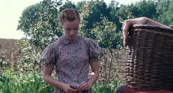 Movie still from “Lore” (2012), directed by Cate Shortland – A young girl in a floral dress standing next to a tree; Medium shot, Over the shoulder angle