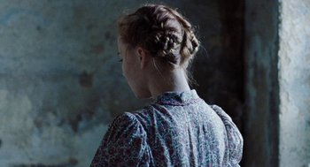 Movie still from “Lore” (2012), directed by Cate Shortland – A woman with a braid in her hair wearing a floral dress; Close Up shot, Over the shoulder angle