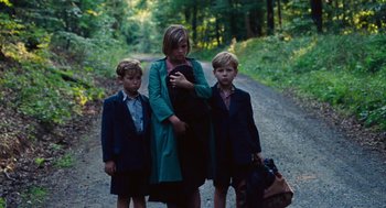 Movie still from “Lore” (2012), directed by Cate Shortland – A woman and two young boys are standing on a dirt road; Medium shot, Low angle