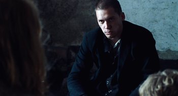 Movie still from “Lore” (2012), directed by Cate Shortland – A man in a black jacket is sitting down; Medium shot, Over the shoulder angle