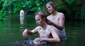 Movie still from “Lore” (2012), directed by Cate Shortland – Two women in a body of water one of them is brushing her hair; Medium shot, Over the shoulder angle