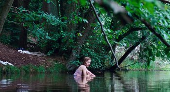 Movie still from “Lore” (2012), directed by Cate Shortland – A woman sitting in the water in the middle of a forest; Extreme Wide shot, High angle