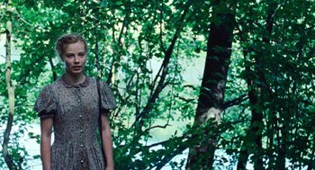 Movie still from “Lore” (2012), directed by Cate Shortland – A woman standing in front of a tree in the woods; Medium shot, Over the shoulder angle