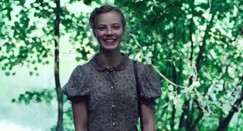 Movie still from “Lore” (2012), directed by Cate Shortland – A woman in a floral dress smiling for the camera; Medium shot, Low angle