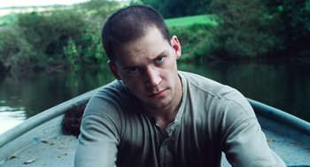 Movie still from “Lore” (2012), directed by Cate Shortland – A person sitting on the ground near a body of water; Close Up shot, Low angle
