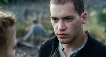 Movie still from “Lore” (2012), directed by Cate Shortland – A young man with a beard is looking at the camera; Close Up shot, Low angle