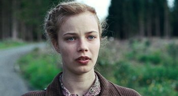 Movie still from “Lore” (2012), directed by Cate Shortland – A young woman with blonde ringlets in a field; Close Up shot, Over the shoulder angle