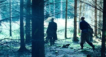 Movie still from “Lore” (2012), directed by Cate Shortland – A man in a black coat standing next to a tree; Wide shot, Over the shoulder angle