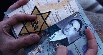 Movie still from “Lore” (2012), directed by Cate Shortland – A person holding a star of david over a picture of a man; Close Up shot, Overhead angle