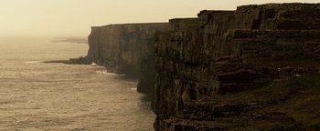 Movie still from “Leap Year” (2010), directed by Anand Tucker – A cliff with a body of water in the background; Extreme Wide shot, High angle