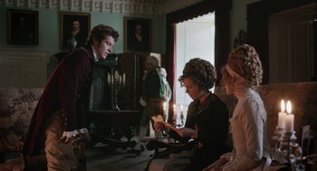 Movie still from “Love & Friendship” (2016), directed by Whit Stillman – A group of people sitting in a living room with candles; Medium shot, Over the shoulder angle