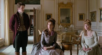 Movie still from “Love & Friendship” (2016), directed by Whit Stillman – A woman sitting in front of a man holding a dog; Medium shot, Over the shoulder angle