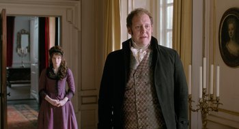 Movie still from “Love & Friendship” (2016), directed by Whit Stillman – A man and a woman standing next to each other in a room; Medium shot, Over the shoulder angle
